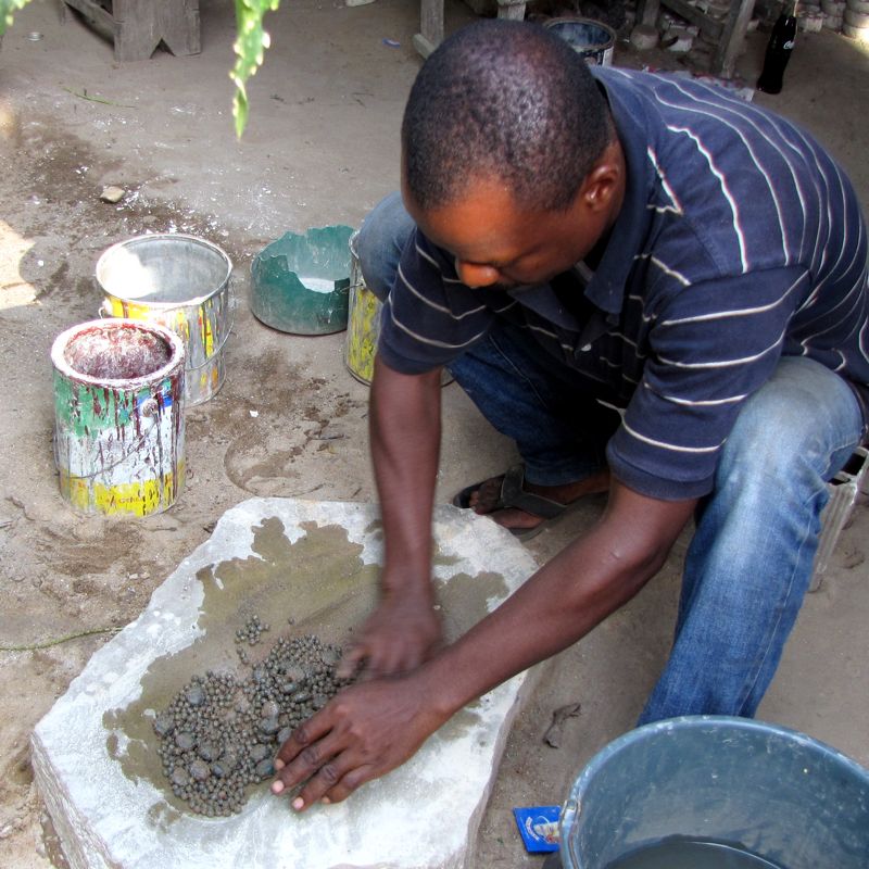 Oklah polishing his recycled bottle glass beads