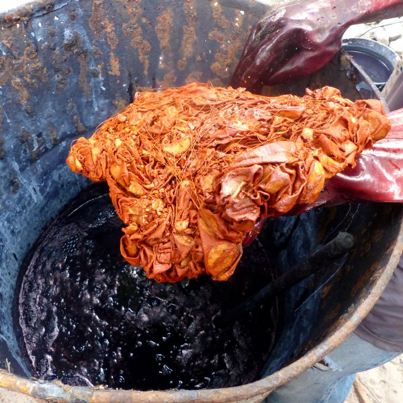 Musa dipping fabric into indigo vat